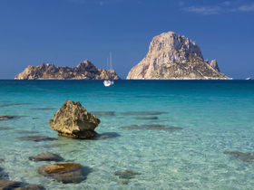 A serene view of a sailboat navigating the turquoise waters near stunning rocky islands, perfect for showcasing the beauty of coastal adventures.