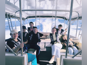 A cheerful family enjoys a boat ride, all wearing life jackets, capturing a fun and safe experience on the water.