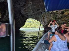 A group enjoys a boating adventure through a scenic cave, capturing memories with their phones — a perfect blend of exploration and fun.