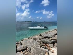 A sleek speedboat is docked in clear turquoise waters, surrounded by rocky shores and a picturesque sky, perfect for a day of adventure on the water.