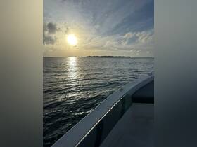 A serene sunset view from the deck of a boat, showcasing the tranquil waters and a distant island — perfect for peaceful evening cruises.