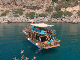 A lively scene featuring a group of swimmers enjoying the clear waters around a beautifully crafted boat, perfect for snorkeling adventures and group outings.