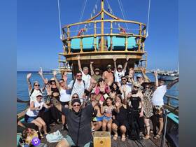 A lively group of friends celebrates aboard a boat, waving and enjoying their time on the water — perfect for memorable outings and gatherings.