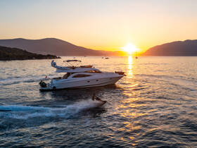 A stunning sunset view featuring a yacht cruising while a water skier glides across the shimmering water, creating an exhilarating scene perfect for adventure seekers.