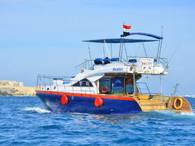 A vibrant view of the 'Drafter' boat cruising through clear waters, showcasing its unique design and inviting atmosphere for potential charters in Egypt.