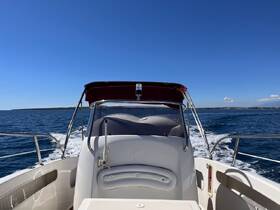A sleek boat cruising through clear waters under a bright blue sky, showcasing the vessel's design and the beauty of a day on the water.