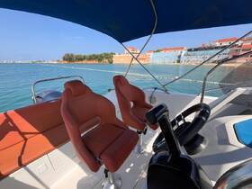 The interior of a boat featuring comfortable seating and a helm, perfect for navigating the waters in style and comfort.