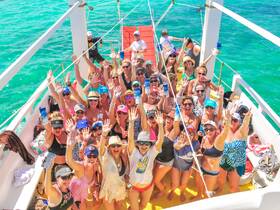 A vibrant group of friends celebrates aboard a boat, waving and enjoying their time on the water — perfect for memorable outings and party experiences.