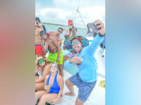 A lively group of friends enjoys a fun day on the water, capturing memories with selfies and drinks aboard a boat — perfect for celebrations and party outings.