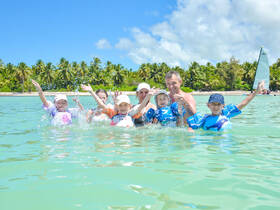 A joyful family splashes in the shallow waters, celebrating together under the sun — a perfect day of fun and laughter at the beach.