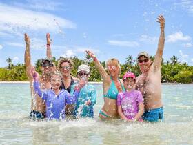 A joyful family splashes in the water, celebrating together under the sun — a perfect moment of fun and togetherness at the beach.