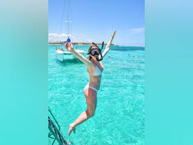 A joyful snorkeler leaps into the crystal-clear waters from a catamaran, capturing the excitement of underwater adventures in a tropical paradise.