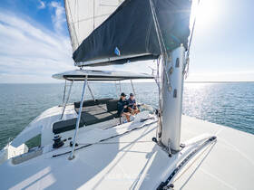 A couple enjoys a relaxing moment aboard a catamaran, surrounded by serene waters and a clear sky — perfect for a day of sailing and leisure.