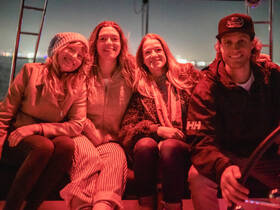 A cheerful group of friends enjoys a night out on the water, capturing the essence of celebration and camaraderie under the stars.
