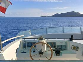 A detailed view of the helm and console inside a boat, showcasing the steering wheel and navigation equipment against a serene ocean backdrop.