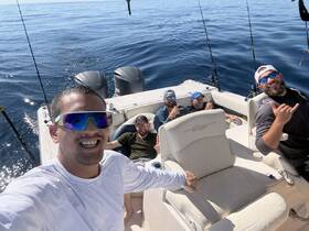 A group of friends enjoys a day of fishing on a boat, capturing the fun and camaraderie under the sun on the open ocean.