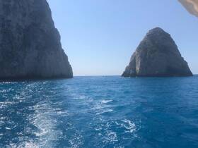 A stunning view of rocky cliffs rising from the vibrant blue ocean, showcasing the natural beauty of the coastline — perfect for scenic boat trips.