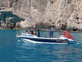 A lively group enjoys a boat ride on the 'Golden Dolphin' along the stunning Greek coastline, capturing the essence of adventure on the water.