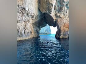 A stunning view of a natural cave opening leading to the open sea, showcasing the beautiful coastline and tranquil waters — perfect for exploring scenic destinations by boat.