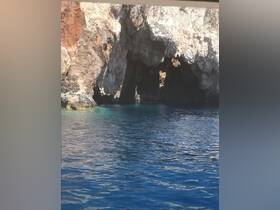 A stunning view of a rocky cave along the coastline, showcasing the beautiful blue waters — perfect for exploring natural wonders while boating.