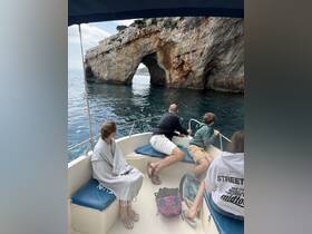 A group of guests enjoys a scenic boat ride, admiring a stunning rock formation while exploring the coastline — perfect for adventure seekers and nature lovers.