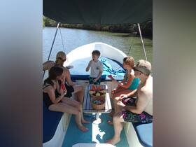 A family enjoys snacks aboard a boat while surrounded by lush mangroves, creating a perfect atmosphere for a fun day on the water.