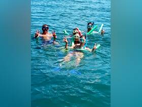 A lively group enjoys snorkeling in clear waters, showcasing fun and camaraderie while exploring the underwater world.
