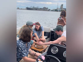A joyful group celebrates with a cake aboard a boat, capturing a memorable moment on the water. Perfect for birthday parties or special gatherings.