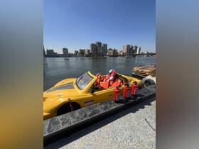 A vibrant yellow boat docked along the river, showcasing its unique design against a backdrop of urban buildings. Ideal for sightseeing or leisure activities on the water.