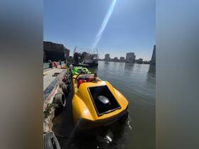 A vibrant yellow speedboat docked along the river, showcasing its sleek design against a backdrop of urban scenery.