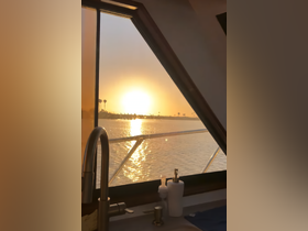 A serene view of a sunset from inside a boat's cabin, showcasing the tranquil waters and palm trees in the distance — perfect for relaxing moments on the water.