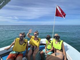 A family prepares for an exciting snorkeling adventure, showcasing their gear and enthusiasm aboard a boat in the beautiful ocean.