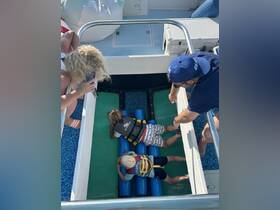 Two children enjoy a playful moment on a boat, engaging with water toys while adults supervise — a perfect snapshot of family fun on the water.