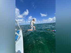 A snorkeler leaps off the side of a boat into the vibrant waters, ready for an exciting underwater adventure. Perfect for thrill-seekers and snorkeling enthusiasts.