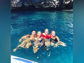 A joyful group of friends enjoys a refreshing swim in crystal-clear waters, capturing the essence of a perfect day on the water.