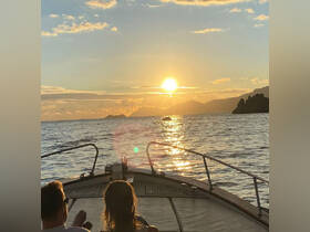 A couple enjoys a romantic sunset view from the bow of their boat, creating a picturesque moment perfect for evening cruises.