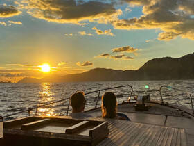 A couple enjoys a romantic sunset view from the deck of a boat, creating a perfect backdrop for memorable moments on the water.