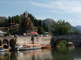 A scenic view of docked boats along a river, with a picturesque backdrop of mountains and greenery, perfect for exploring the natural beauty of the area.