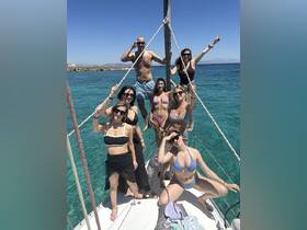 A lively group of friends poses on the bow of a boat, enjoying a sunny day on the water — perfect for summer celebrations and memorable outings.