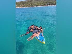 A lively group enjoys paddleboarding in crystal-clear waters, capturing the essence of summer fun and adventure on the beach.