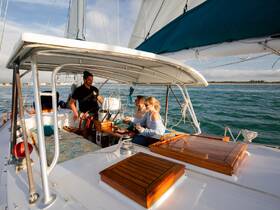 A couple enjoys a relaxing sailing experience on a yacht, sharing cocktails and laughter as they take in the beautiful views — perfect for romantic outings or sunset cruises.