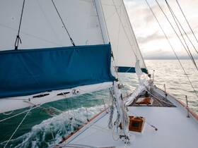 A stunning view from the front of a sailboat as it glides through calm waters, showcasing the intricate rigging and sails against a serene backdrop.