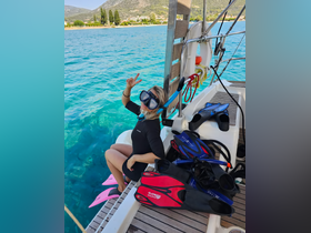 A woman prepares for snorkeling with fins and mask on the side of a boat, showcasing the excitement of water adventures in a beautiful turquoise setting.