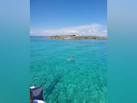 A person enjoys swimming in the crystal-clear waters near a picturesque island, showcasing the beauty of a perfect day on the water.