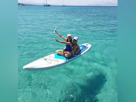 A joyful couple enjoys paddleboarding in crystal-clear waters, capturing the essence of fun and adventure on the water.