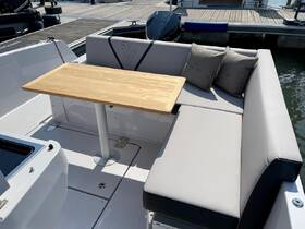 A stylish seating area inside a boat featuring a wooden table and comfortable cushions, perfect for dining or relaxing while on the water.