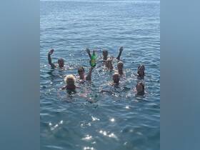 A lively group enjoys a fun day in the water, celebrating together with drinks in hand — perfect for summer outings and memorable adventures.