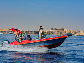 A lively group enjoys a thrilling ride on a speedboat, showcasing the excitement of on-water adventures against a scenic backdrop.