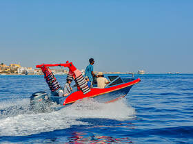 A lively group enjoys a thrilling ride on a speedboat, showcasing the excitement of on-water adventures against a picturesque coastal backdrop.