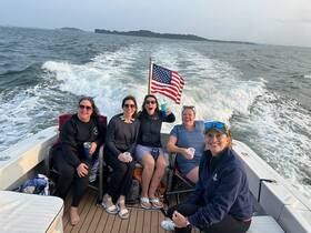 A lively group of friends enjoys a fun day on the water, celebrating with drinks aboard a boat, showcasing the joy of summer outings.